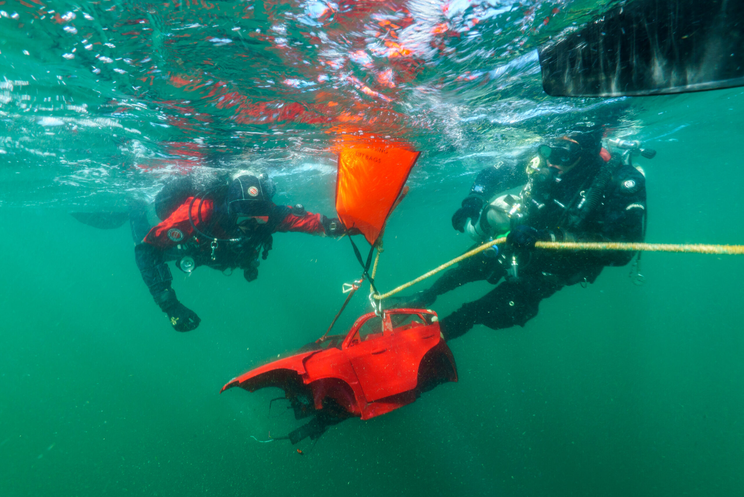 Duikers halen auto onderdelen van speelgoedauto's uit zee